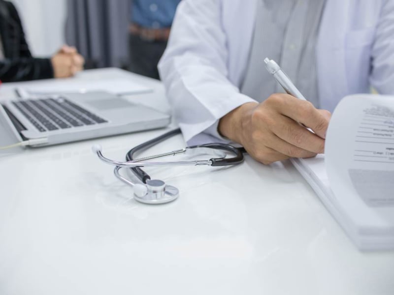 Doctor writing and recording patient data